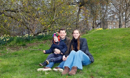 Nicholas Binge with his son, Oskar, and partner Allys, sitting on a grass with trees behind