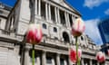 A photograph from a low angle of the impressive pillared facade of the Bank of England, with spring flowers in the foreground
