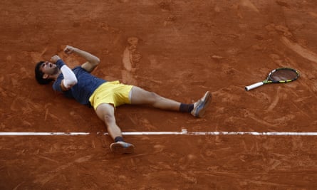 Alcaraz drops to the clay in joy and celebration.