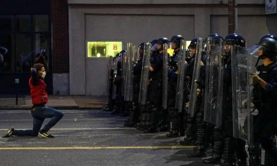 A man gets on his knees in front of police officers during a protest against the death of George Floyd, in St Louis, Missouri.
