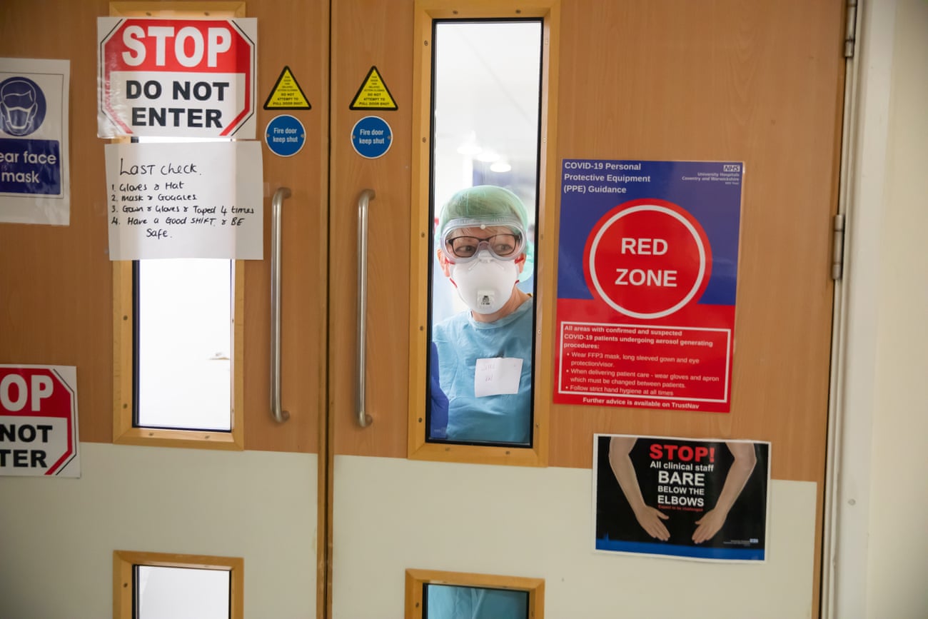 A medic looks out from ITU, where signs warn of the extreme infection risk within.