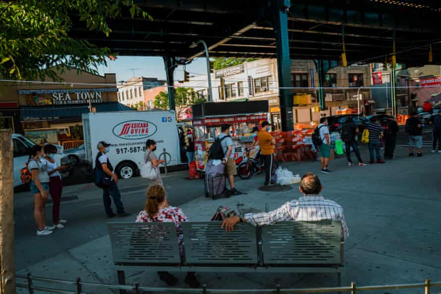 People wait in line for a bus in Corona, Queens.