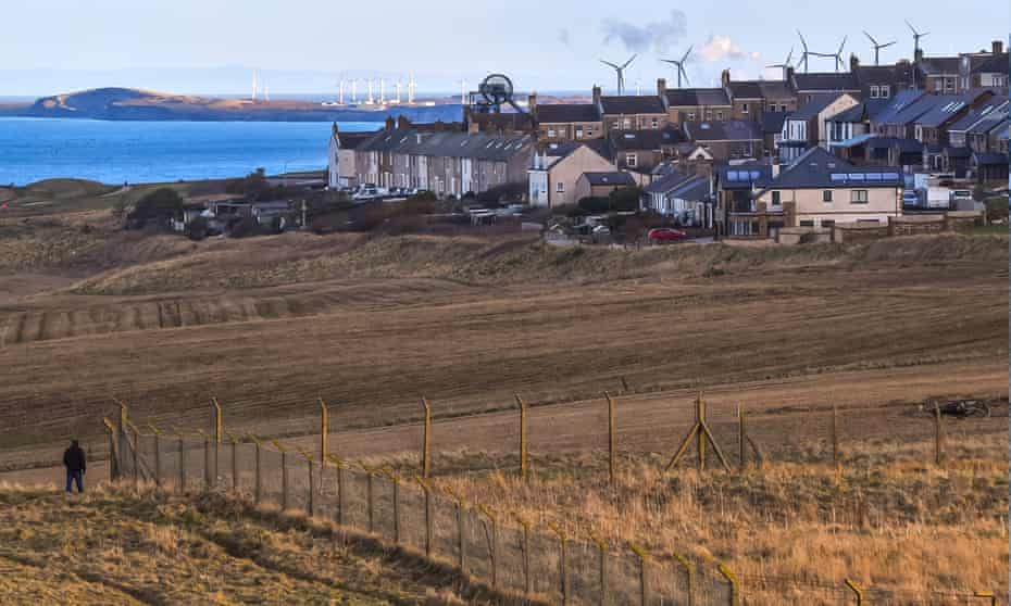 A pedestrian walks along the coastal path beside the proposed site of a new coalmine in Whitehaven, Cumbria