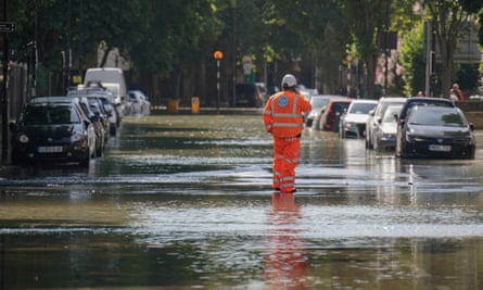 A Thames Water official stands in flood water in north London, after a 36-inch water main burst