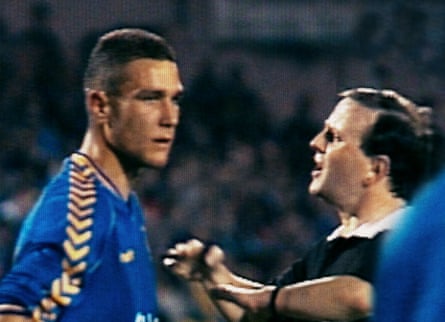 A footballer being talked to by a referee