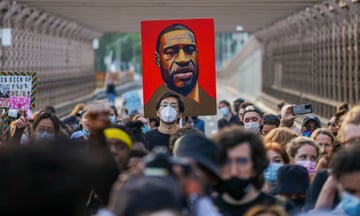 Marching demonstrators hold up a painting of George Floyd's face