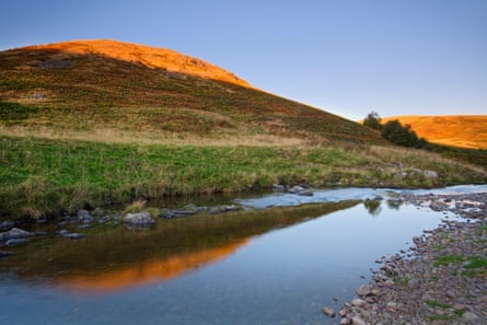 A river runs past hills in a remote area of Northumberland