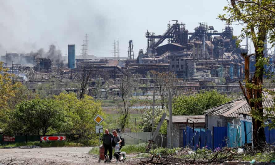 It’s unclear what the exact circumstances are with these people pictured on 11 May, but they are in Mariupol with their belongings and, in the background, are the damaged facilities of the Azovstal Iron and Steel Works.