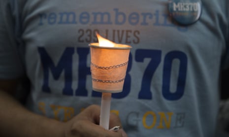 在纪念马来西亚航空公司 MH370 航班失踪周年纪念活动期间,游客手持点燃的蜡烛向失踪乘客致敬