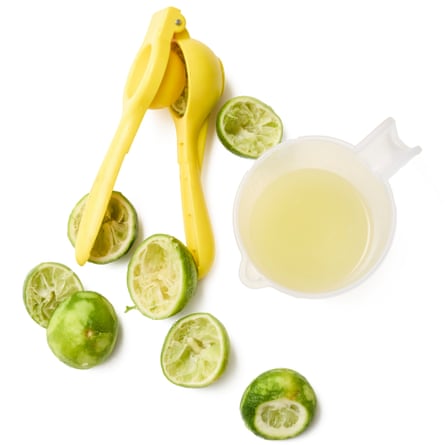 A lime squeezer, with squeezed limes and a jug of lime juice