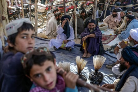 Men gather around bags containing heroin and hashish as they negotiate and check quality at a drug market on the outskirts of Kandahar