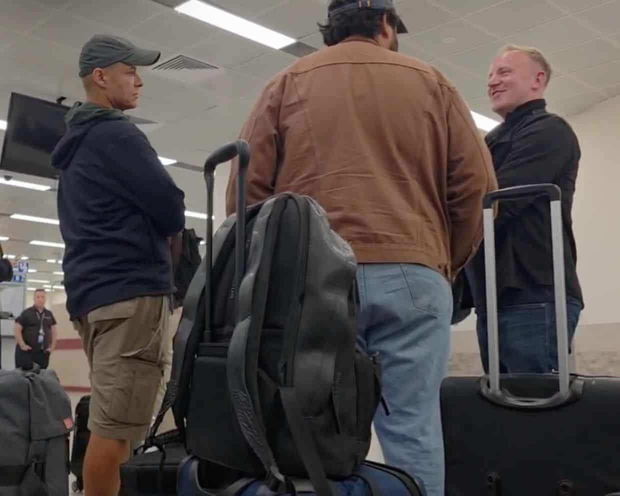 Lewis and Tarry stand with luggage in the checkpoint