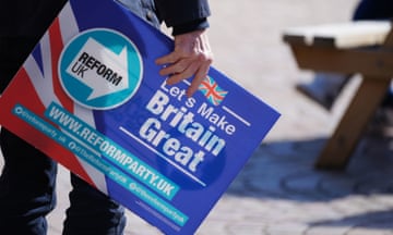 A man holds a placard in Blackpool during a Reform UK campaign event