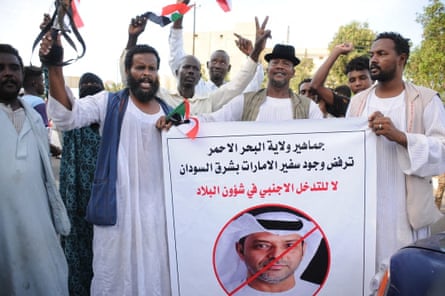 People dressed in white robes protesting against the UAE's influence in Sudan. A slogan written in Arabic on a banner reads: 'The people of (Sudan’s) Red Sea state reject the presence of the UAE ambassador in eastern Sudan. No to the foreign interference in the country’s affairs.'