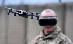 Soldier wearing a headset controls a small drone mounted with a camera.