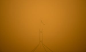 The Australian flag on top of Parliament House is seen surrounded by smoke haze early morning in Canberra