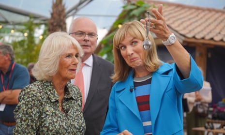 Fiona Bruce makes a face as she holds up a pendant, watched by Camilla, the Queen Consort.