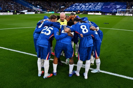 Chelsea players huddle while surrounding referee Paul Tierney.