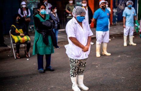 Employees of the Ciudad de Dios market wait to be tested by health ministry workers in Lima, Peru, on 11 May. 
