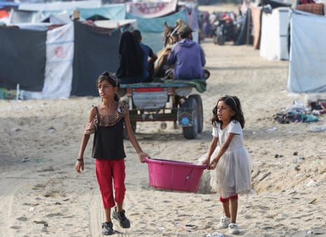 Girls carry a container as Palestinians flee Rafah due to an Israeli assault on Thursday.