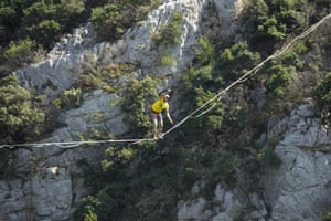 A man with a Tour de France t-shirt walks a tightrope as riders pass during the fourteenth stage of the Tour de France