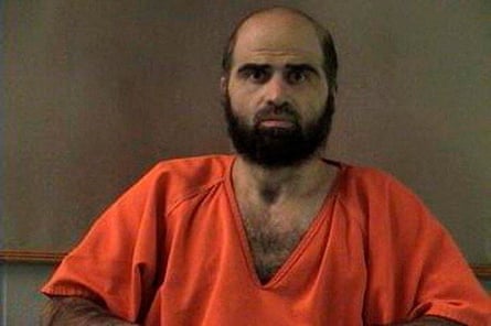 Nidal Husan wears an orange prison shirt. He is balding but has a thick dark beard.