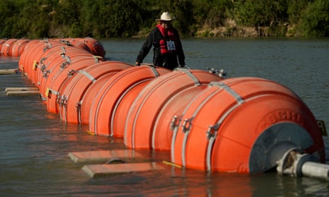 A kayaker walks past large buoys being used as a floating border barrier on the Rio Grande, in Eagle Pass, Texas. 