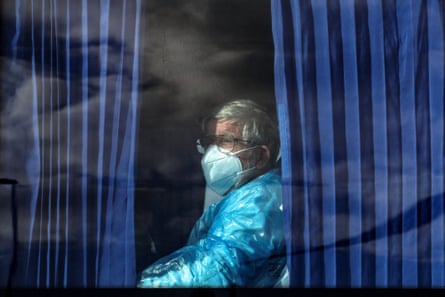 a person in personal protective gear looks out of a bus window