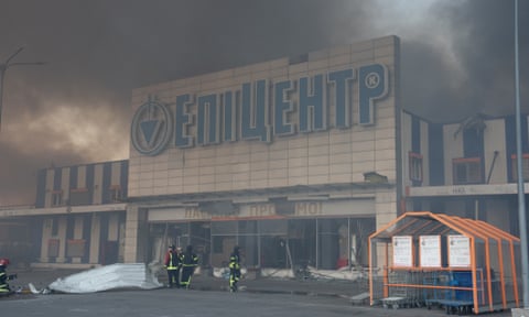 Zjarrfikësit qëndrojnë përpara një hipermarketi 'Epicentr K' pas një sulmi ajror rus në Kharkiv, Ukrainë.