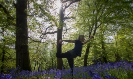 woman doing a yoga pose in bluebell woodland