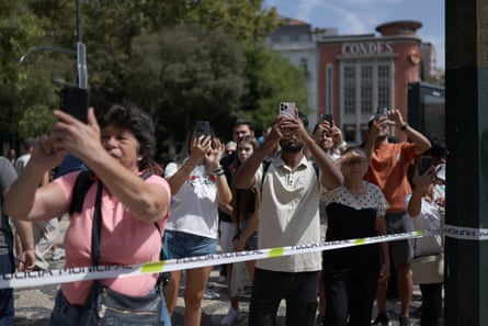People hold smartphones aloft as they take photos