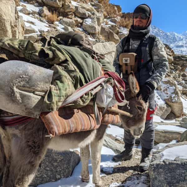 A man stands with a laden donkey on a rocky mountain trail