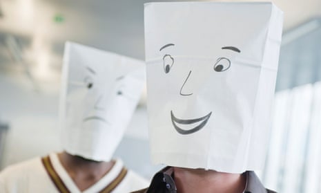 Two men wearing paper bags of happy and sad faces
