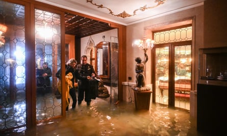 An employee of the Gritti Palace helps a customer walk across the flooded entrance during an exceptional “Alta Acqua” high tide