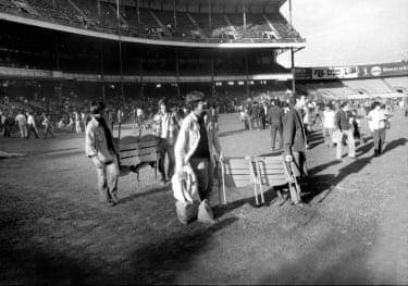 People carry seats on a baseball field