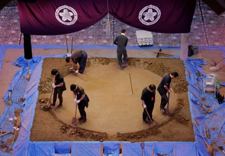 Yobidashi dig a shallow trench around the outside of the ring before dropping in the tawara.