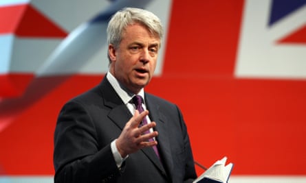 Andrew Lansley duke qëndruar përpara një flamuri sindikal