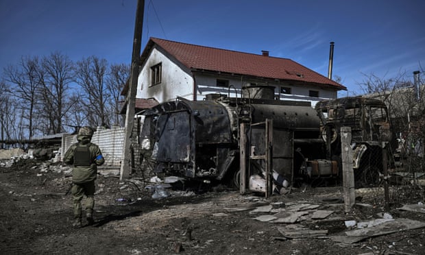 An Ukranian serviceman walks past a destroyed Russian vehicle in a village east of Kharkiv on Monday
