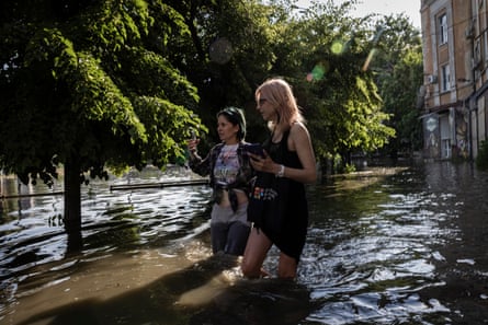 Two women wade through rising flood water in central Kherson.