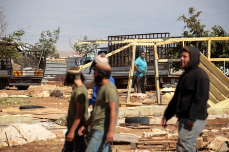 Settlers walk around the villagers’ houses.