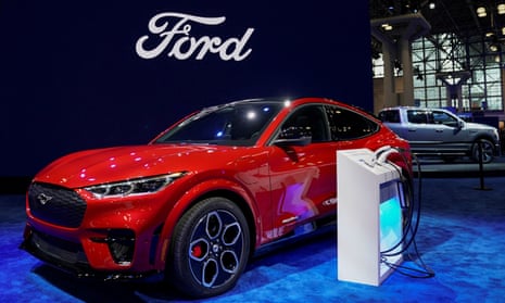 Red car next to white charging station on blue carpet