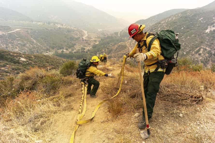 Members of the Mormon Lake Hotshots from Arizona lay hose line down rugged terrain off Highway 39 in front of the Bobcat fire.
