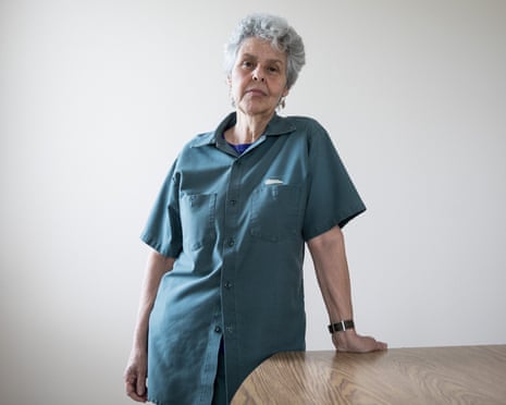 Judith Clark, in a prison work shirt, stands by a wooden table