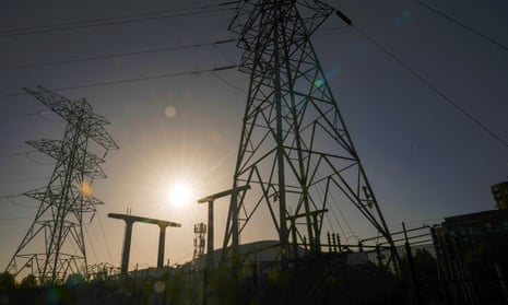 The sun rises behind electricity pylons and a substation in Manchester