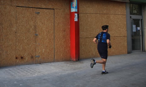 A runner passes a boarded-up shop in London