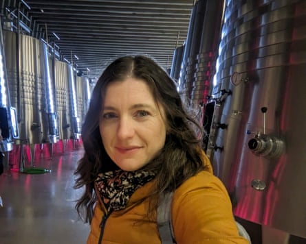 Woman in orange coat surrounded by wine vats at winery cellar in Spain
