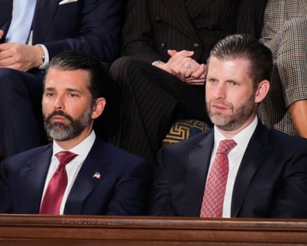 Donald Trump Jr and Eric Trump seated while wearing dark suits with red ties