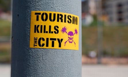 A sticker saying “Tourism kills the city” with a skull and crossbones image on a post in Barcelona