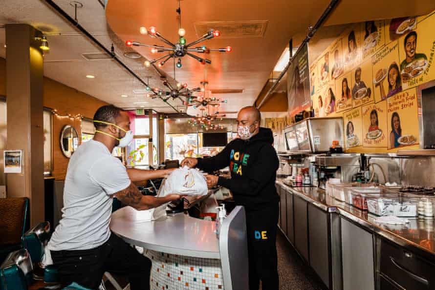 A man hands another man a takeout order