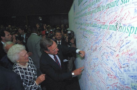 A man in a suit adds his name to a wall of signatures